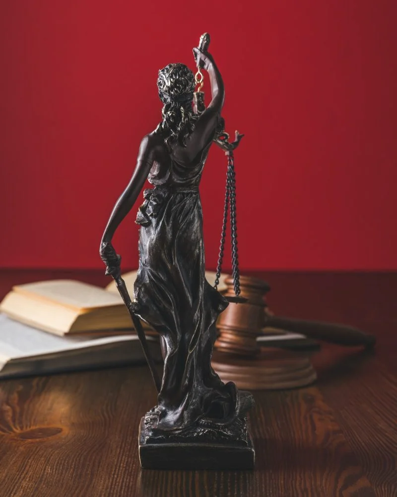 Bronze Lady Justice statue beside legal books